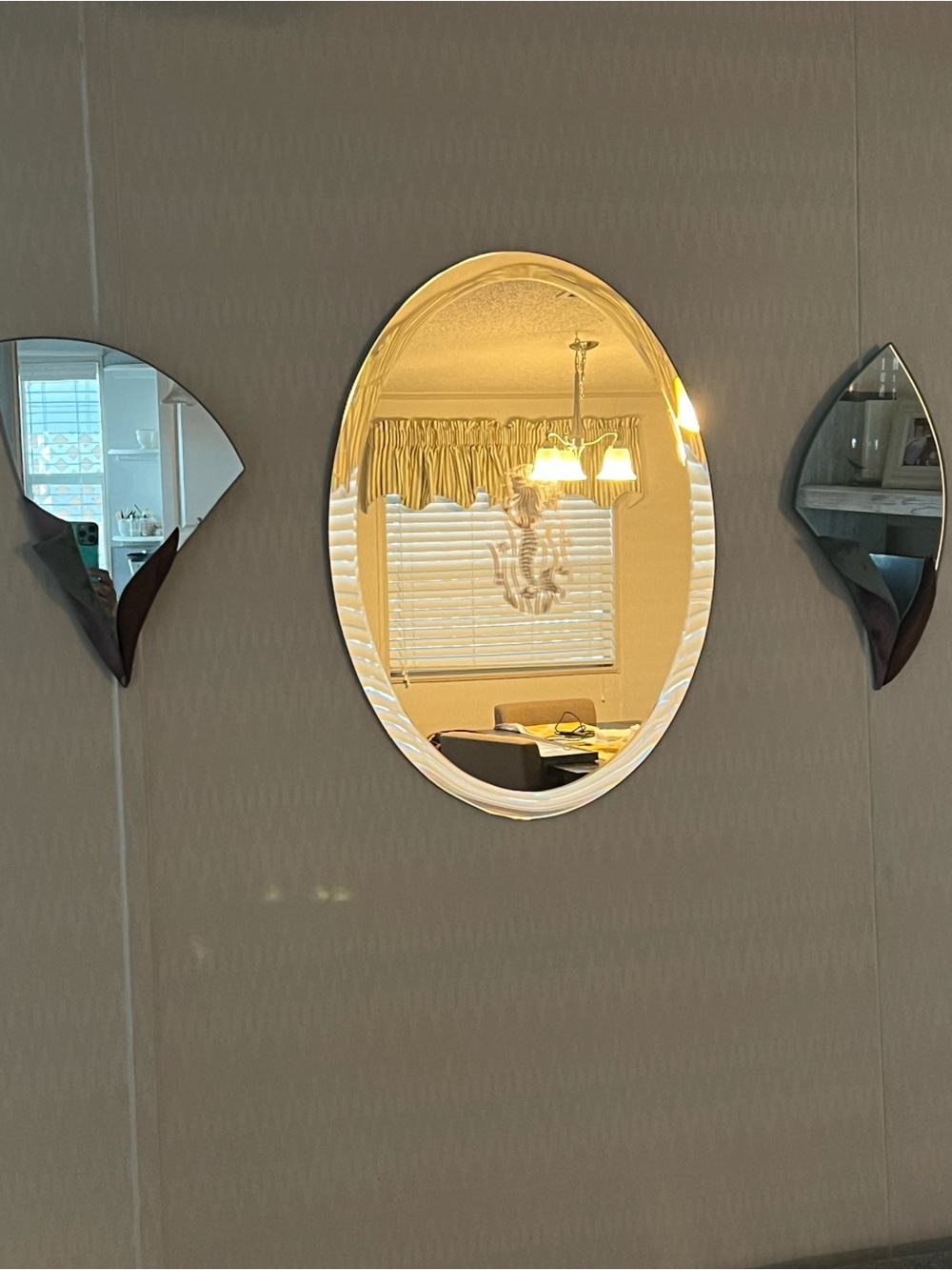 A frameless oval mirror with a mermaid etching with 2 matching mirrored sconces